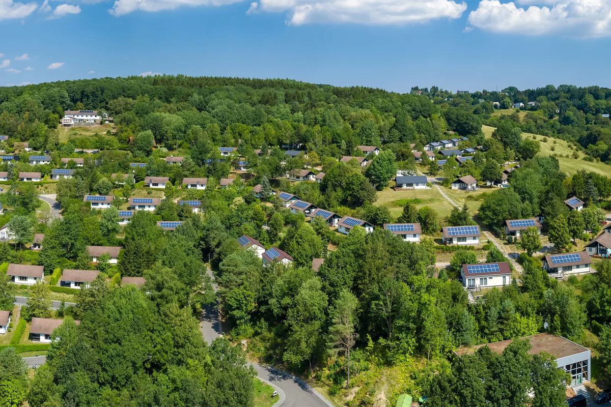 Luftbild: Ferienhäuser zwischen Bäumen an einem Hang in der Eifel