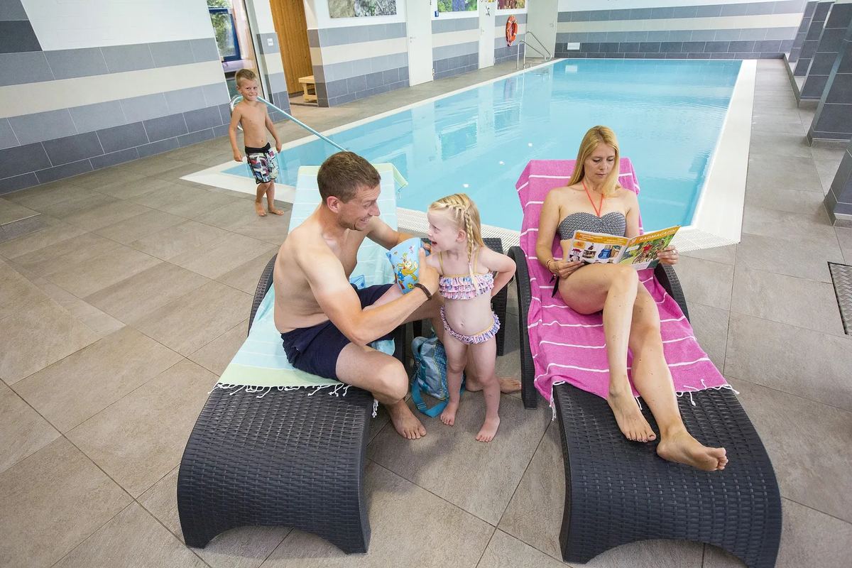 Familie auf Liegen am Hallenbad
