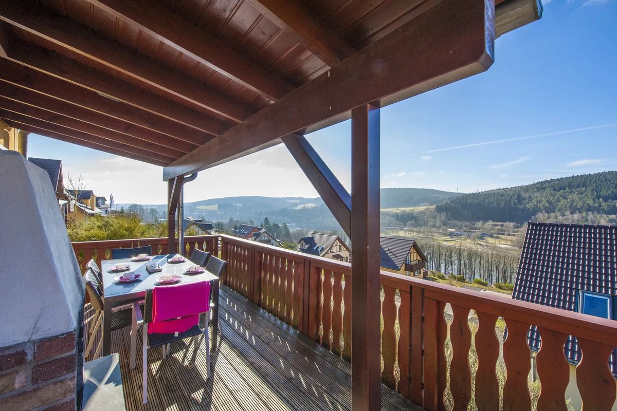 Überdachter Holzbalkon mit Tisch und Blick über die Hügel