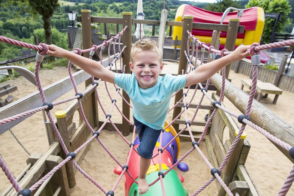 Junge auf einer Hängebrücke am Spielplatz