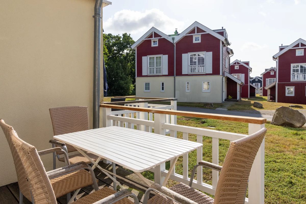 Balkon mit Tisch vor roten Holzhäusern