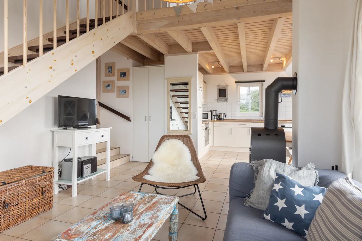 Wohnzimmer mit Sofa, Ofen und Treppe zur Galerie