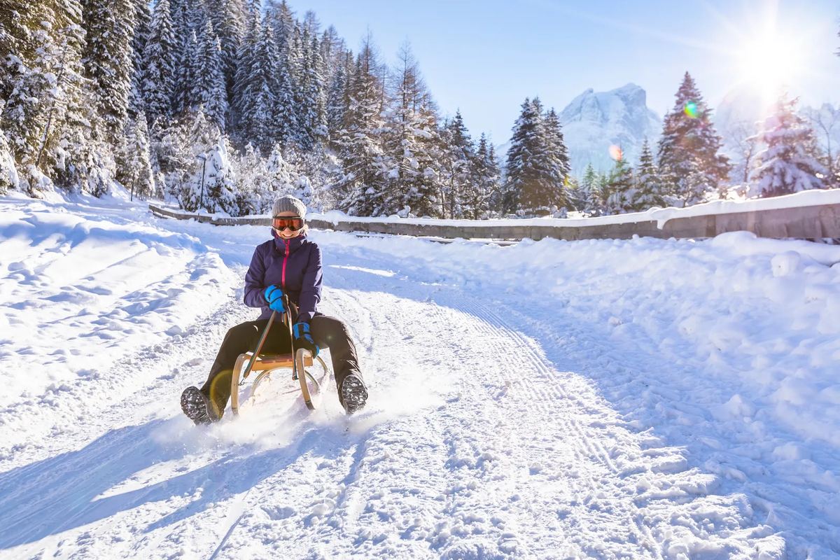 Person rodelt einen verschneiten Weg hinunter