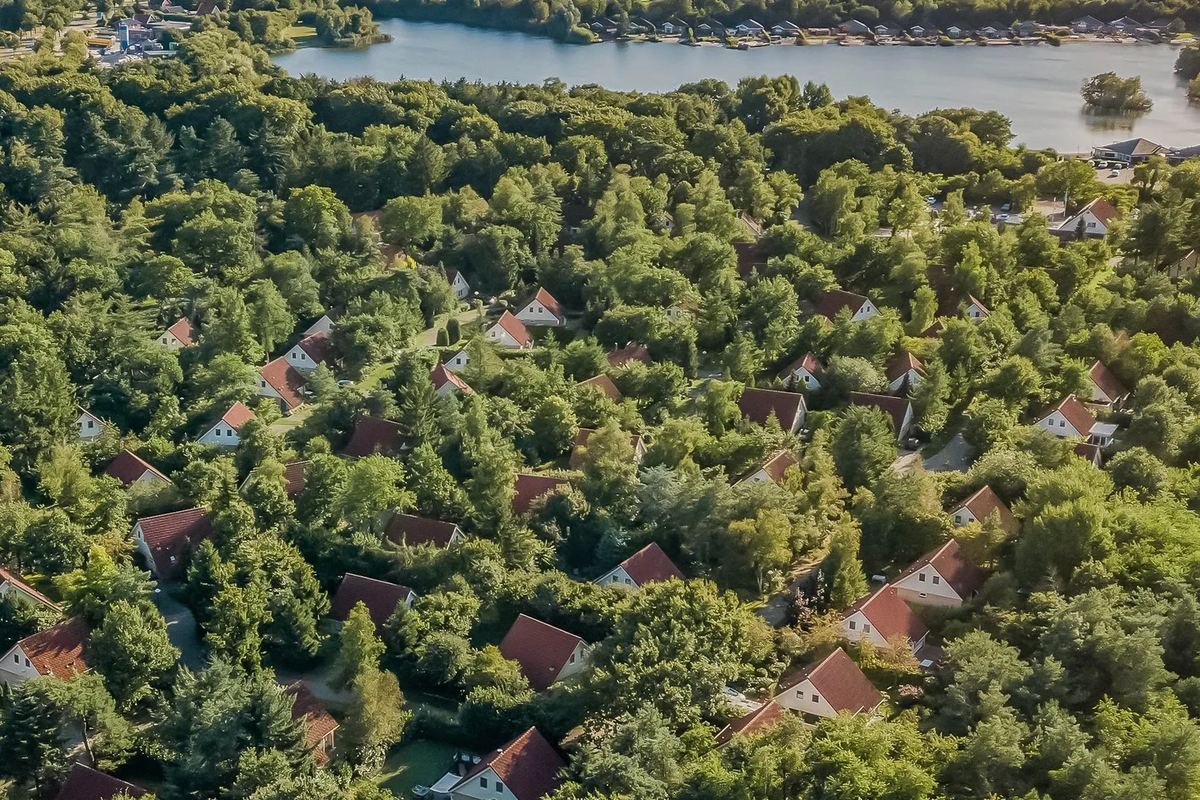 Luftbild: Ferienhäuser mit roten Dächern im Wald nahe einem See
