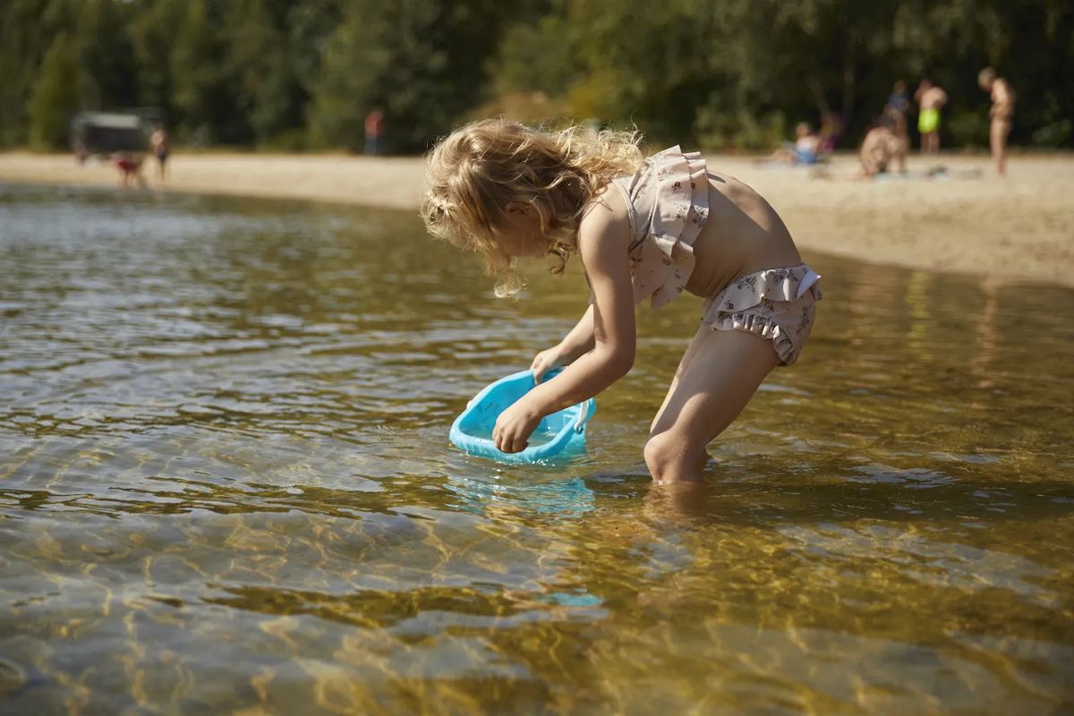 Kind spielt im flachen Wasser am Sandstrand