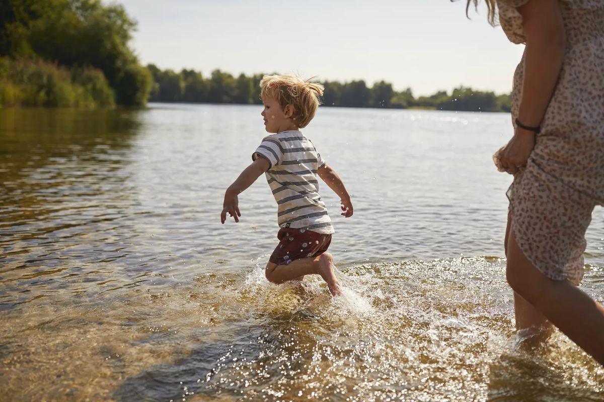 Junge läuft ins Wasser eines Sees