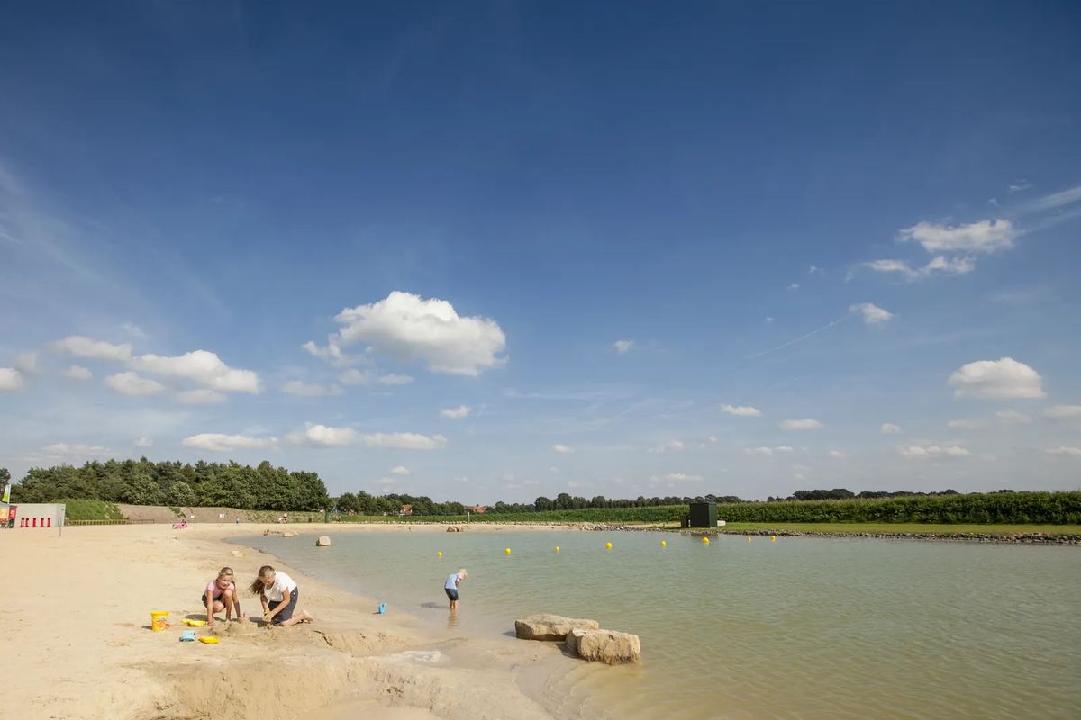 Badesee mit Sandstrand und Kindern am Ufer
