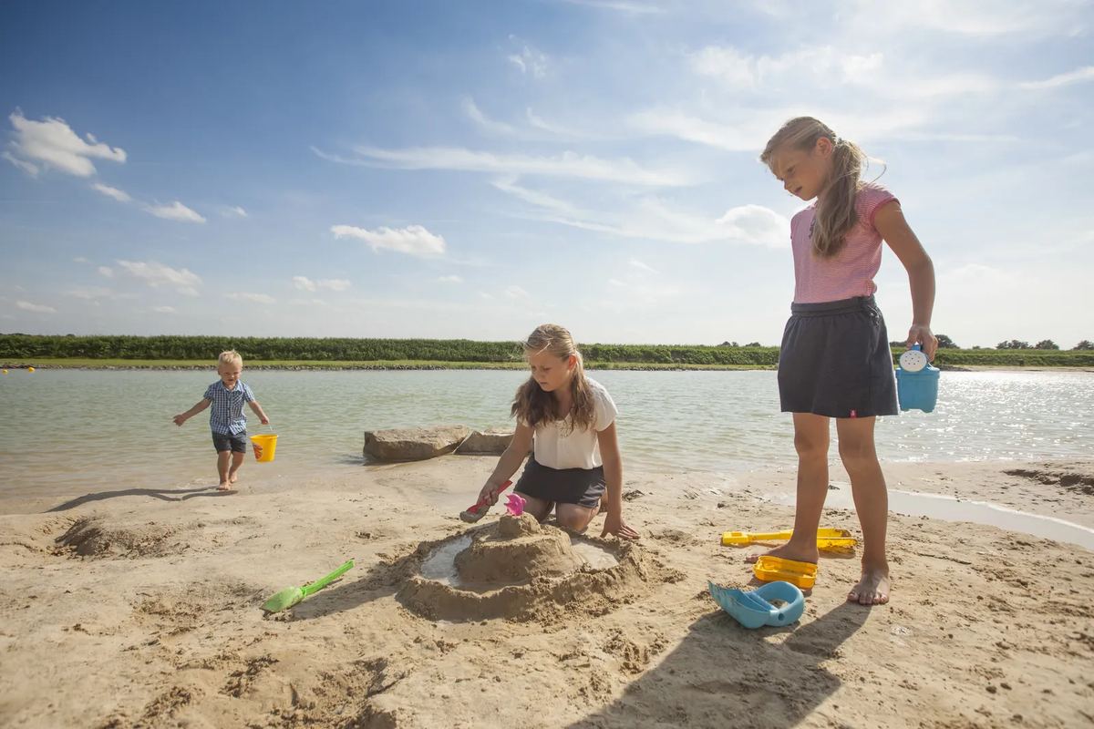 Kinder bauen am Seeufer im Sand