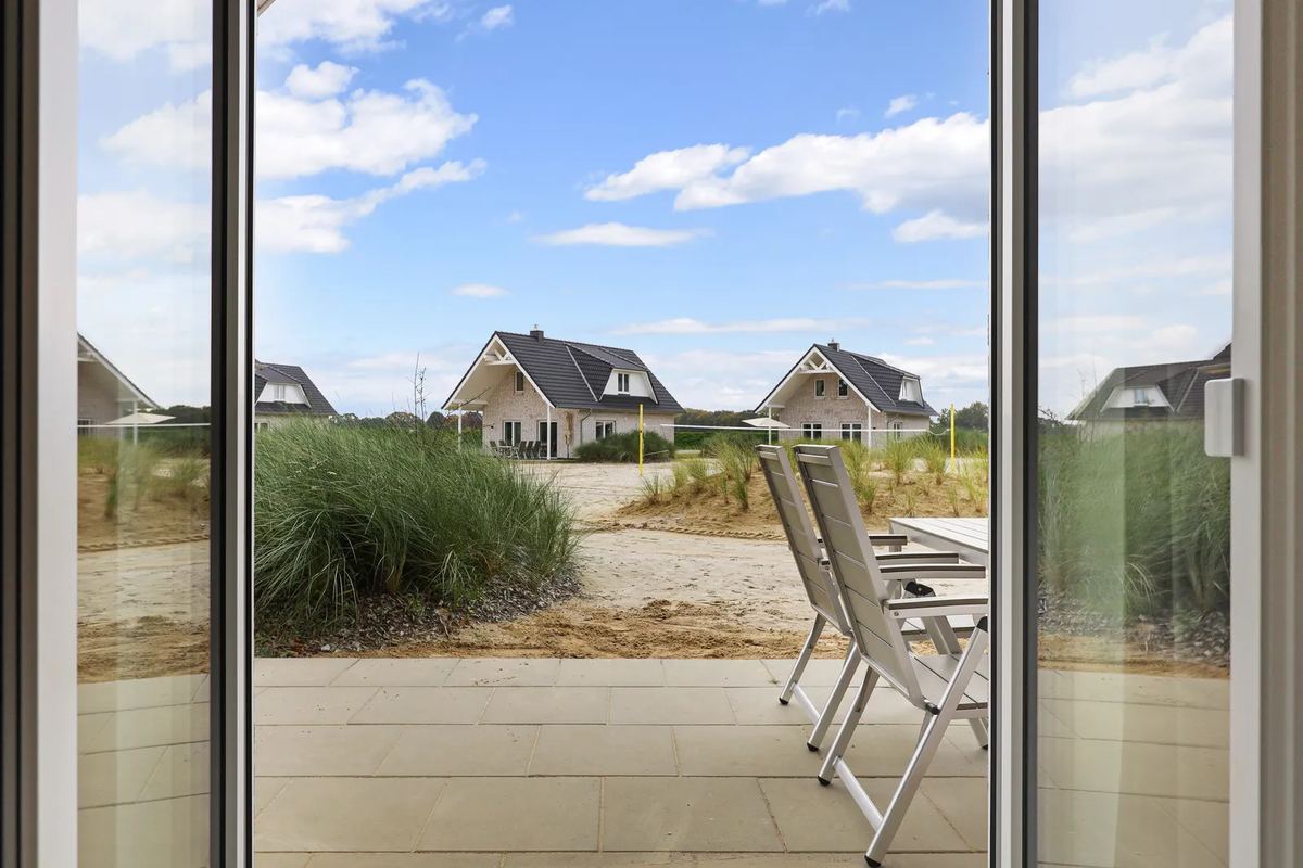 Blick durch eine Glastür auf Terrasse und Nachbarhäuser