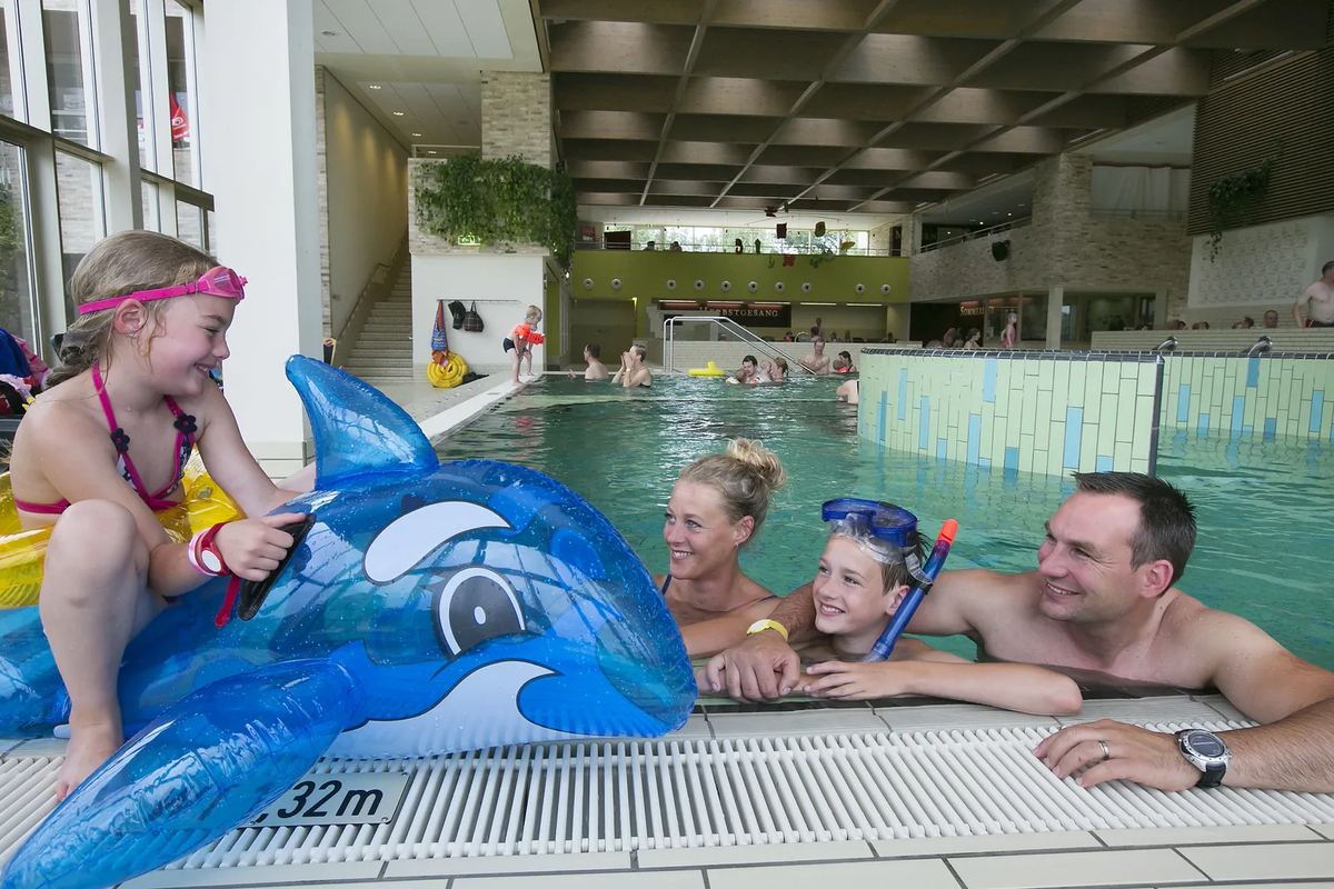 Familie im Hallenbad mit aufblasbarem Delfin
