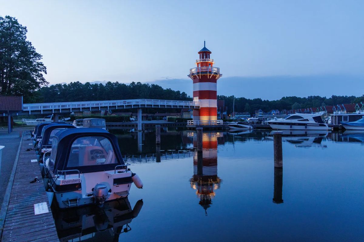 Leuchtturm und Boote im Hafen in der Abenddämmerung
