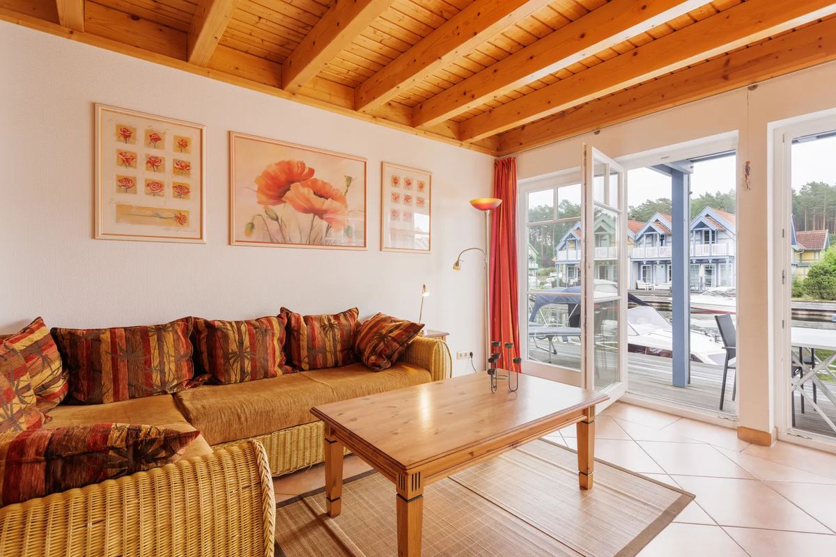 Wohnzimmer mit Holzdecke, Sofa und Blick aufs Wasser