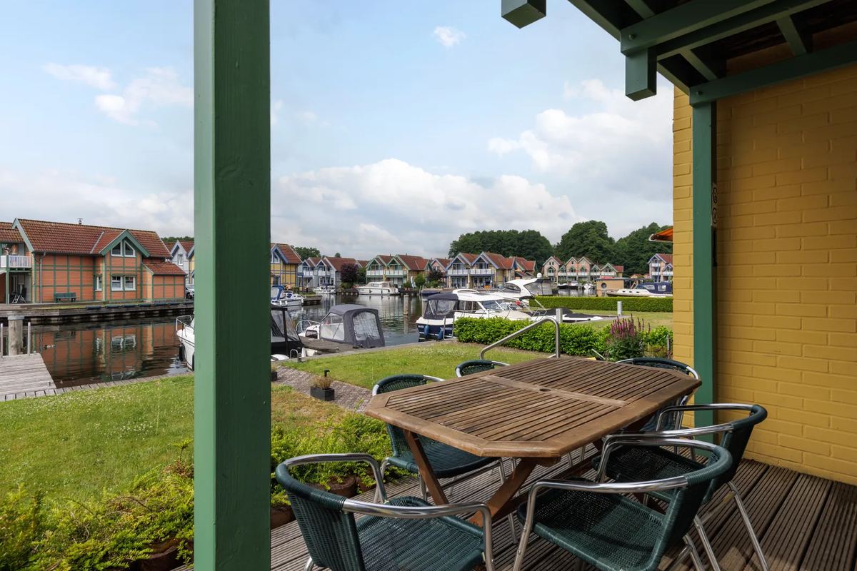Überdachte Terrasse mit Tisch und Blick auf den Hafen