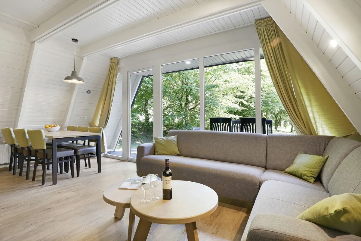 Wohnzimmer mit Sofa und großem Fenster unter dem Spitzdach