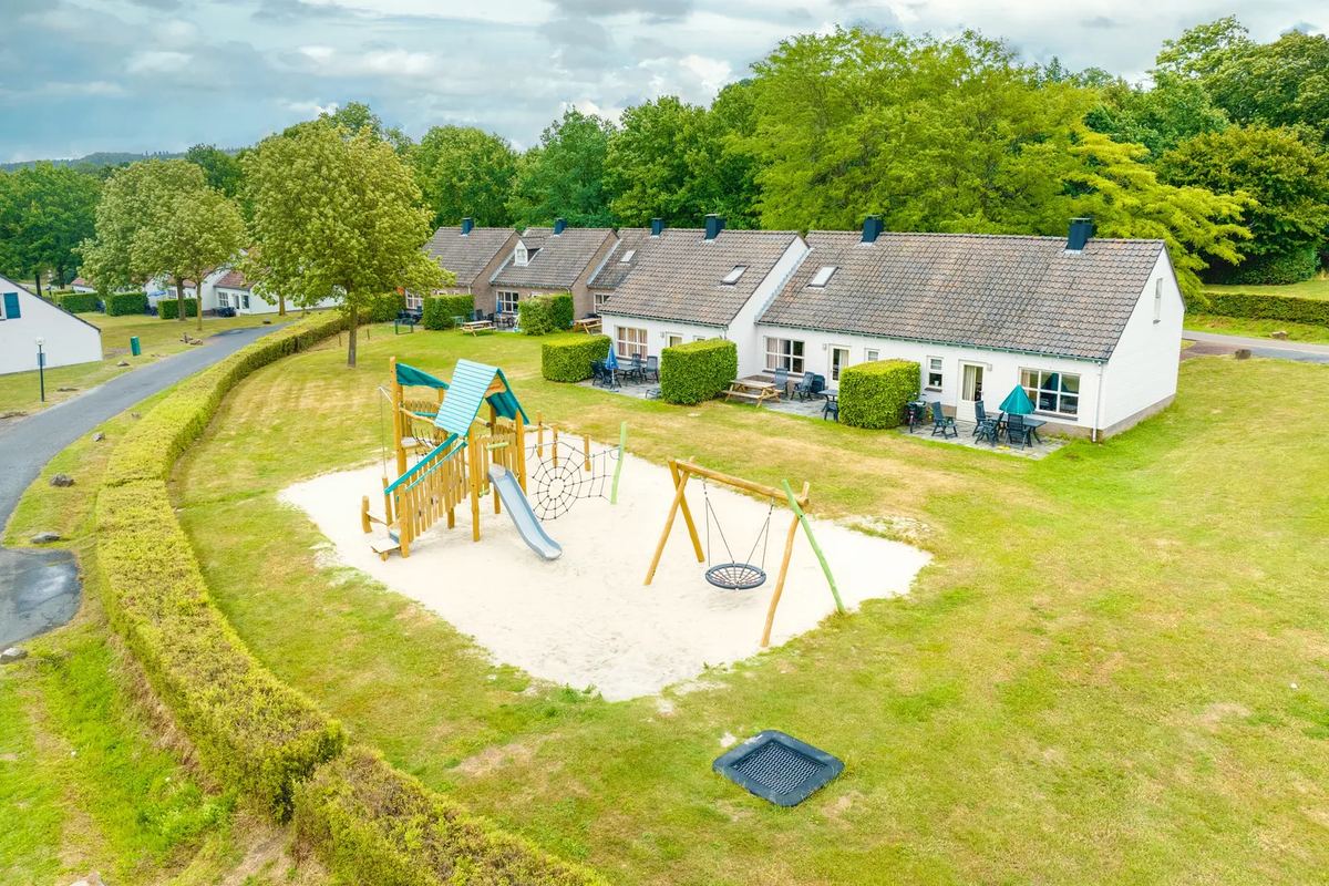 Spielplatz mit Sandfläche vor einer Reihe Ferienhäuser