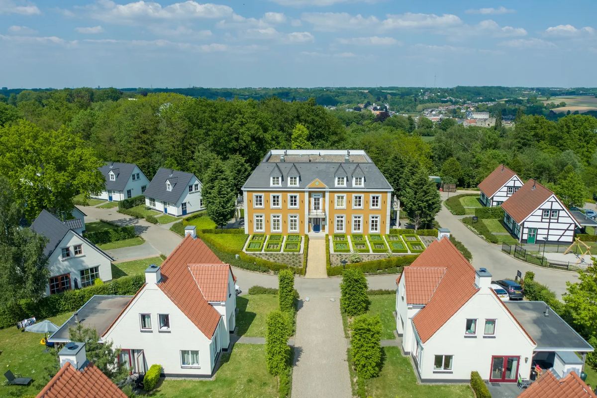 Luftbild: Schlossgebäude zwischen weißen Ferienhäusern
