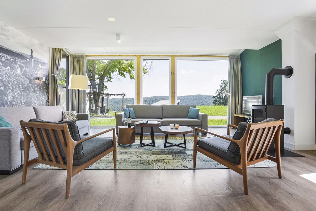 Helles Wohnzimmer mit Sesseln, Sofa und großen Fenstern