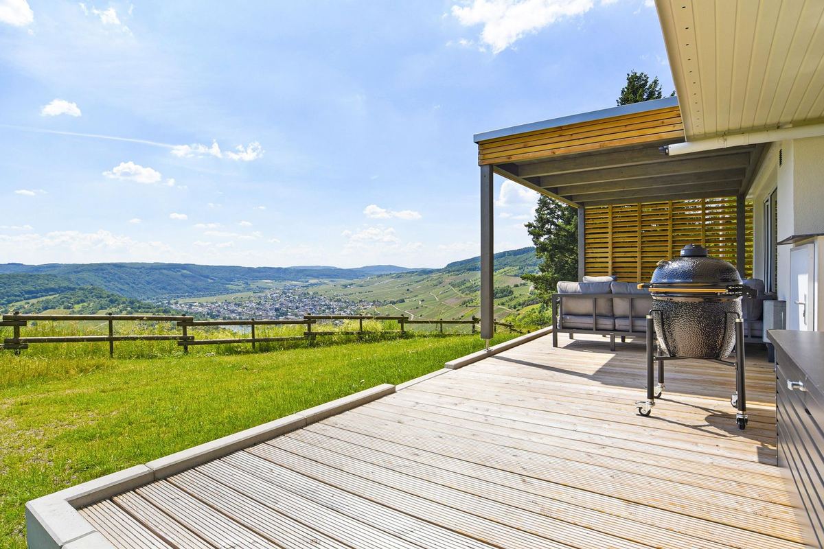 Holzterrasse mit Grill und Blick über Hügel und Tal