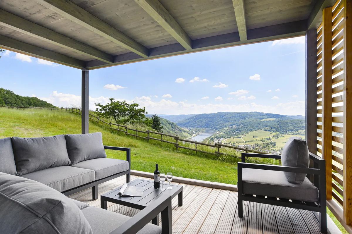 Überdachte Terrasse mit Loungemöbeln und Blick ins Tal