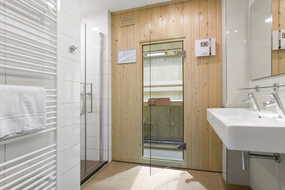 Badezimmer mit Dusche, Waschbecken und kleiner Saunakabine