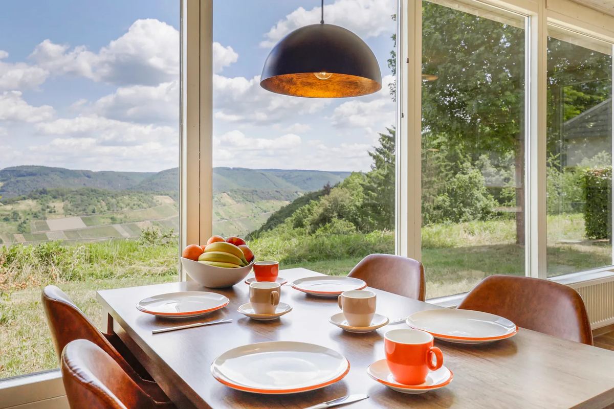 Gedeckter Esstisch vor Panoramafenstern mit Blick ins Tal