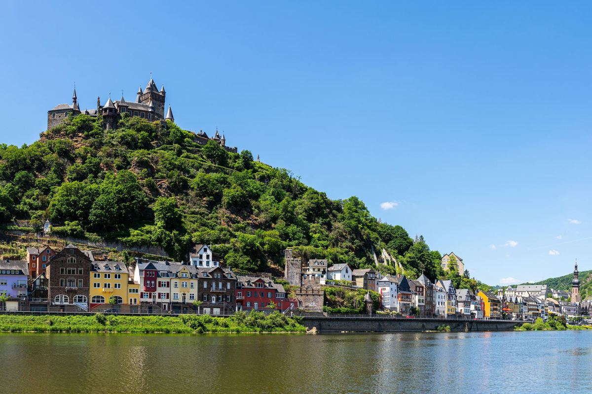 Ort am Moselufer, darüber eine Burg auf dem Berg