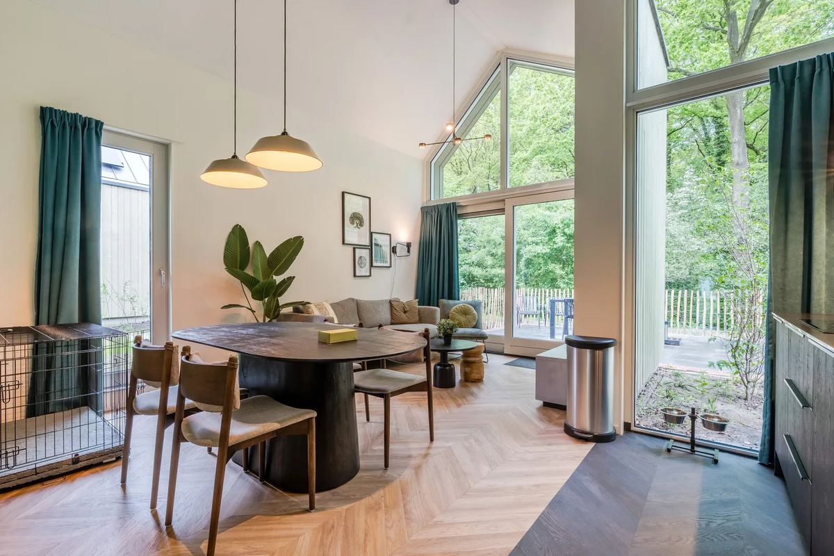 Hoher Wohnraum mit Essbereich und großen Fenstern