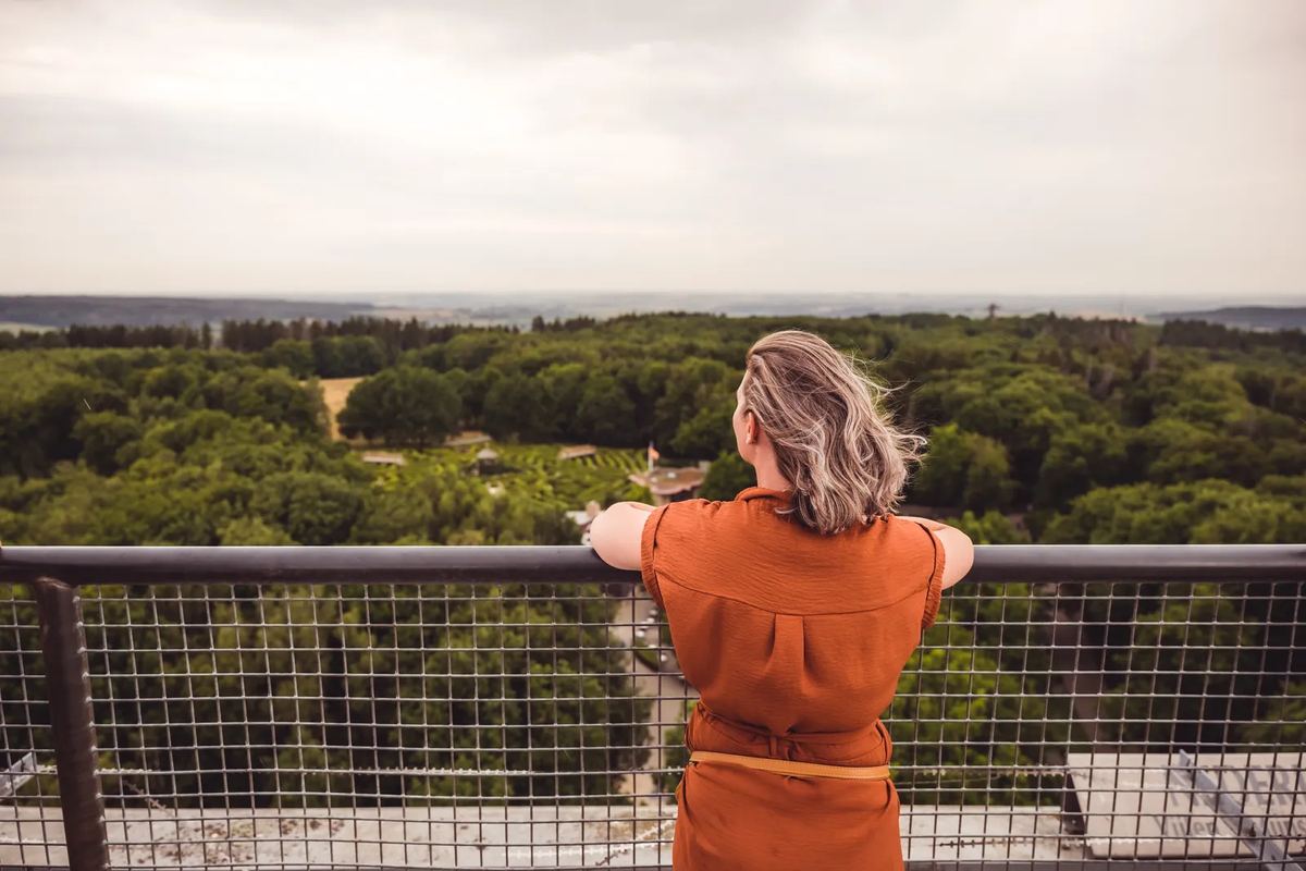 Frau auf einer Aussichtsplattform über Wald