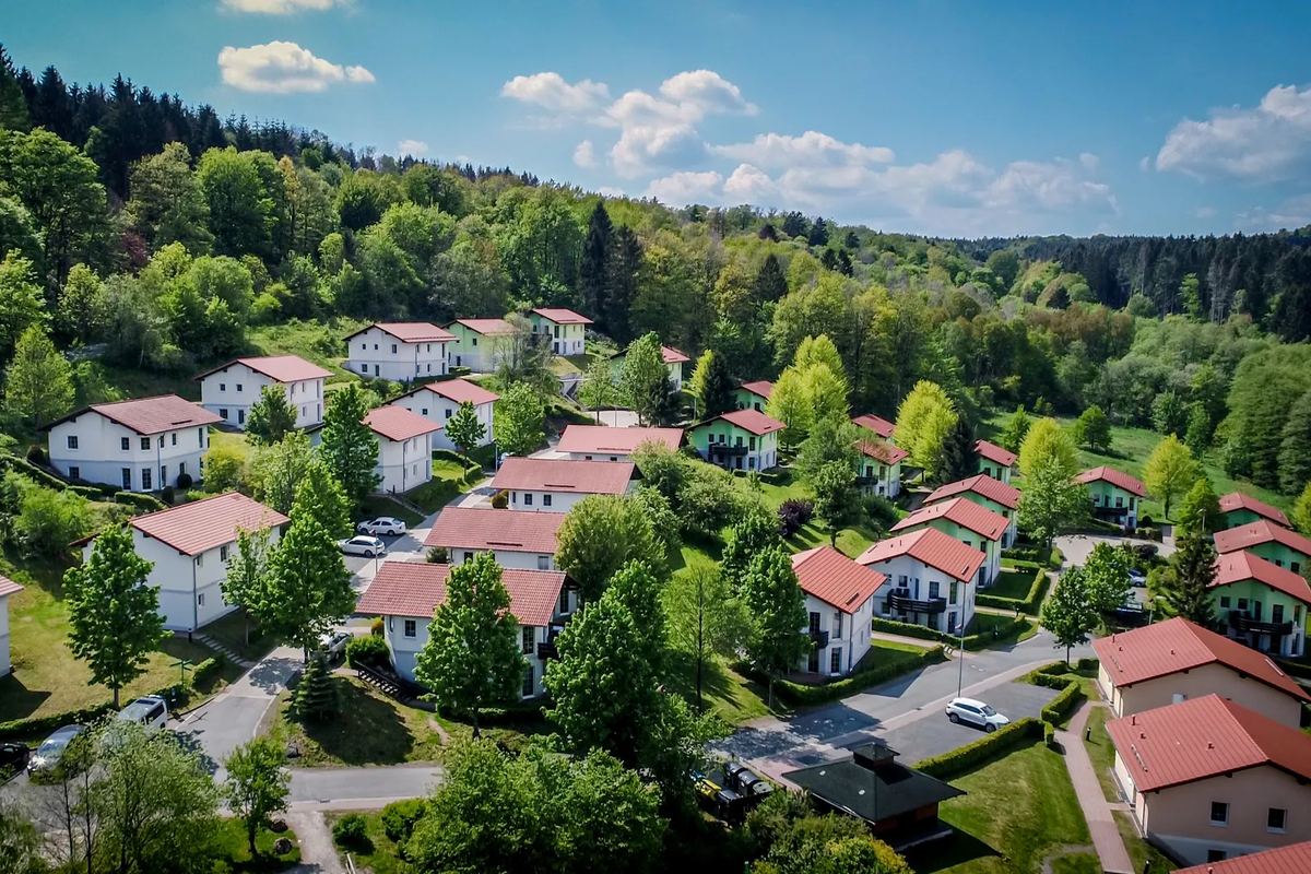 Luftbild: Ferienhäuser mit roten Dächern zwischen Wäldern