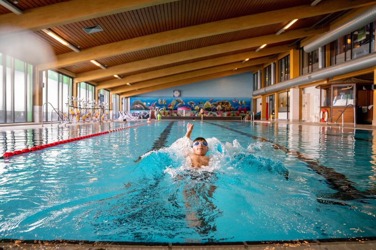 Schwimmer im langen Becken unter einem Holzdach