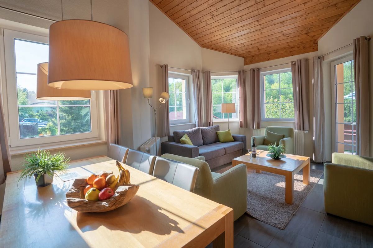 Wohnzimmer mit Holzdecke, Sofa und Esstisch