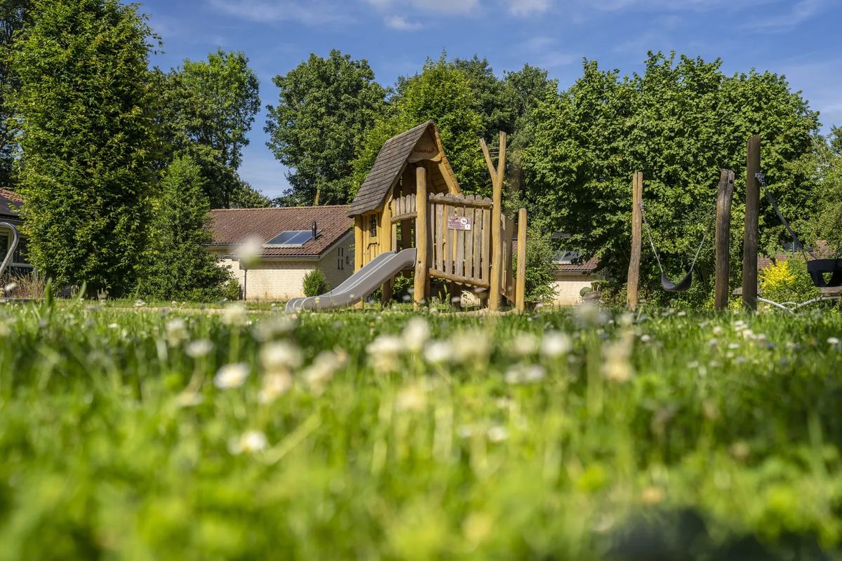 Spielplatz mit Holzturm auf einer Wiese