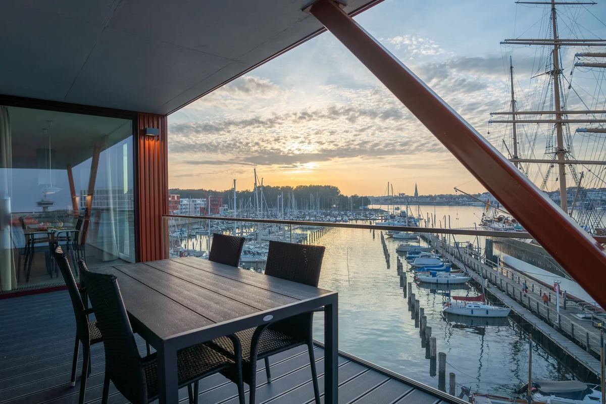 Balkon mit Tisch und Blick auf den Jachthafen bei Sonnenuntergang