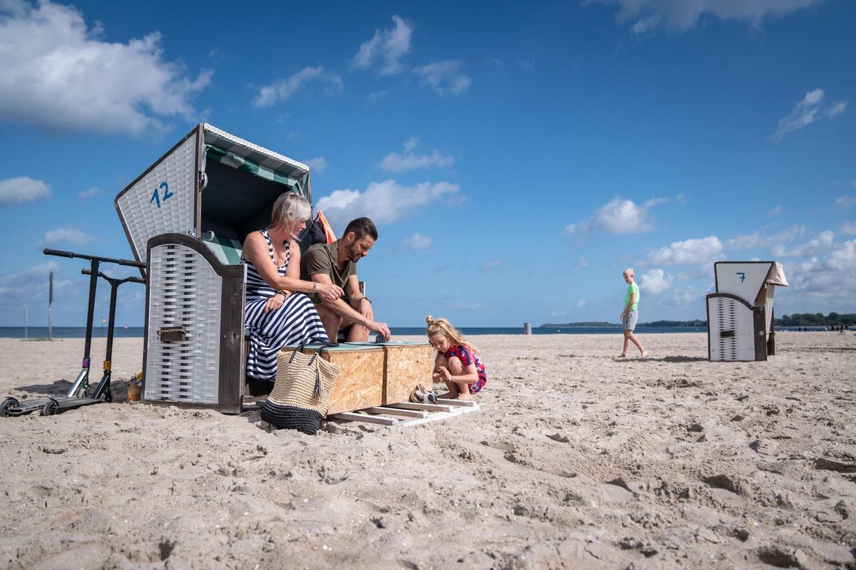 Familie am Strandkorb im Sand