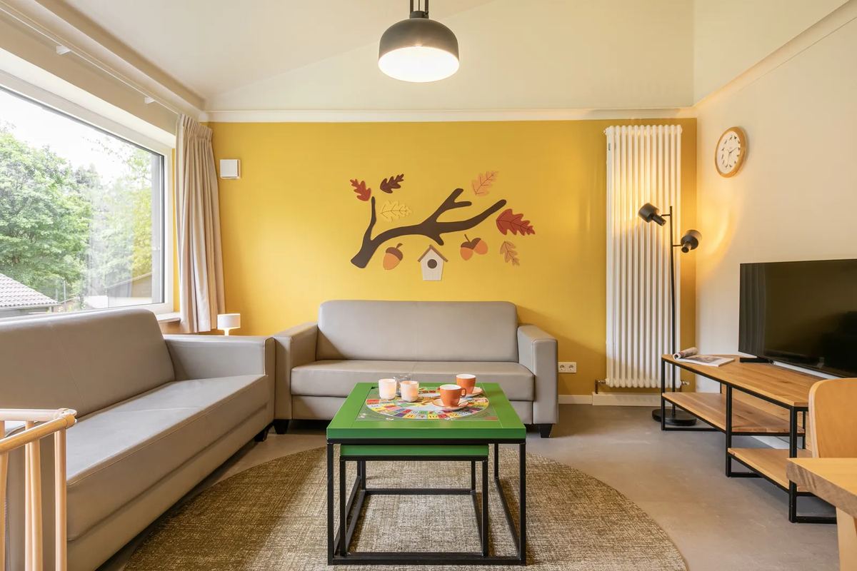 Wohnzimmer mit gelber Wand und Sofas