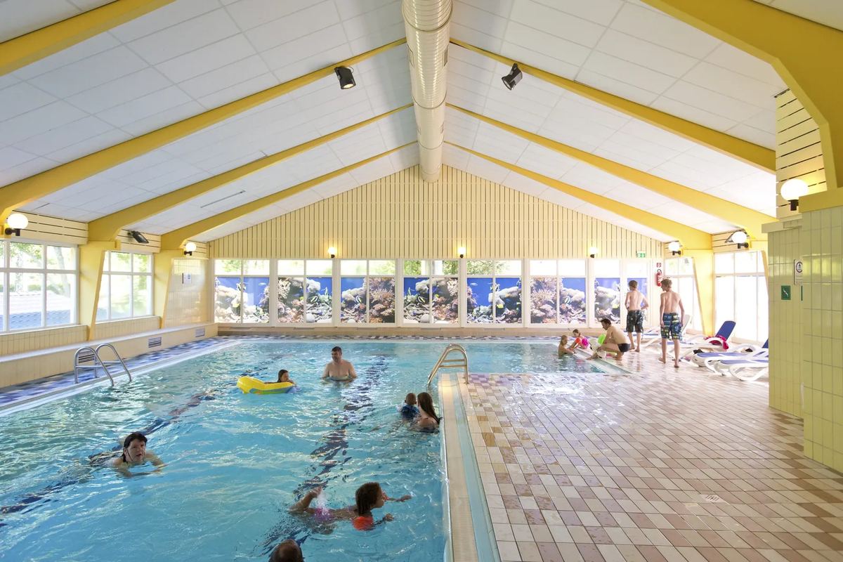 Hallenbad mit Schwimmbecken unter einem Holzdach