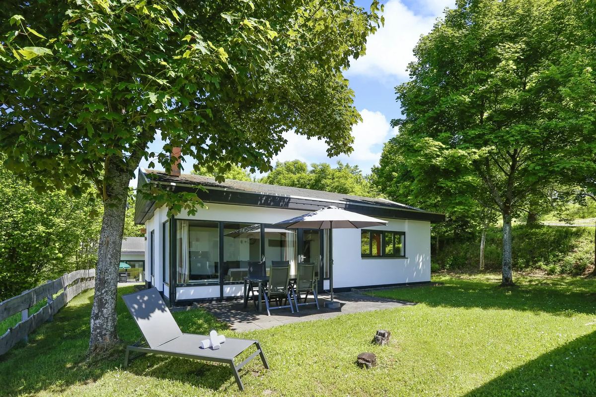 Flaches Ferienhaus mit Liegestühlen auf dem Rasen